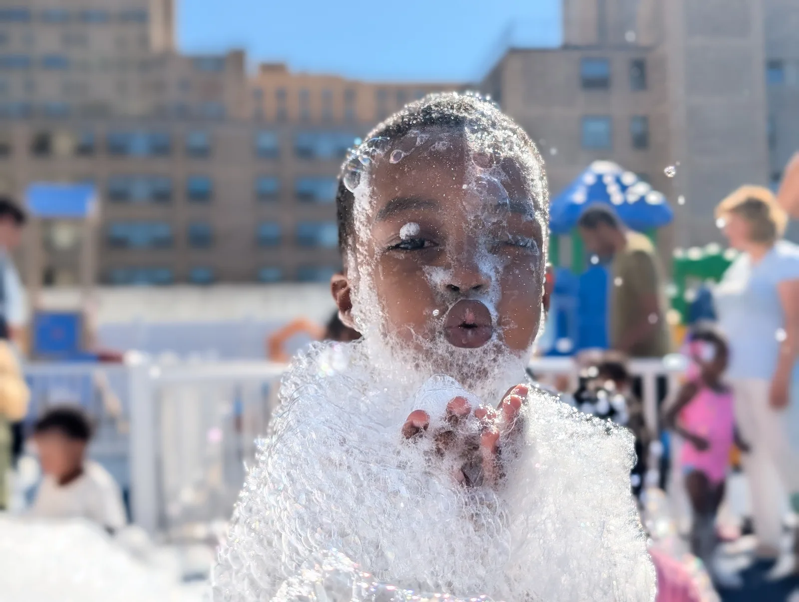 A child with foam piled across their hands and face